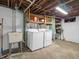 Basement laundry area with white washer and dryer, utility sink, and open shelving for storage at 87 S 10Th Ave, Beech Grove, IN 46107