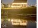 Lakefront home with string lights on the patio and a reflection in the water at night at 8755 Stoddard Ln, Indianapolis, IN 46217