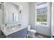 Bright bathroom featuring a marble countertop vanity, a decorative mirror, and a window offering a pleasant outdoor view at 961 Starkey Rd, Zionsville, IN 46077
