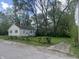 View of a small, single-story home surrounded by mature trees and a chain-link fence at 1105 N Livingston Ave, Indianapolis, IN 46222