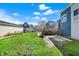 A green backyard and a driveway near a house with an attached, covered patio, and a blue house at 1422 Olive St, Indianapolis, IN 46203