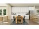 Modern dining area seamlessly connected to the kitchen, featuring a wooden table, black chairs, and a view of the living room at 15388 Manderley St, Fishers, IN 46040