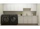 A laundry room featuring a dark washer and dryer set with ample cabinet space and countertop for folding at 15388 Manderley St, Fishers, IN 46040