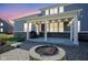 Captivating backyard at dusk with a stone fire pit, outdoor lights, and a charming covered patio at 15594 Garrano Ln, Fishers, IN 46040