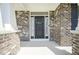 Close-up of front door with decorative wreath, sidelights and brick facade under a covered porch at 15594 Garrano Ln, Fishers, IN 46040