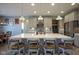 Kitchen island features quartz countertop, brick accent, and seating; pendant lights add elegance at 15594 Garrano Ln, Fishers, IN 46040