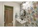 Well-lit bathroom featuring a floral accent wall, gray vanity, and round mirror at 1583 Valdarno Dr, Greenwood, IN 46143
