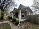 A quaint home featuring a covered porch, wooden fence, and mature trees in a serene setting at 1626 S State Ave, Indianapolis, IN 46203