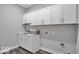 Laundry room with white cabinets, sink, gray walls and modern wood look flooring at 19414 Mcbee Ave, Westfield, IN 46074