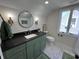 Bathroom featuring stylish green vanity, round mirror and updated fixtures at 2029 Winton Ave, Indianapolis, IN 46224