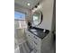 Bright bathroom with granite counters, white cabinets and an updated circular mirror at 2029 Winton Ave, Indianapolis, IN 46224