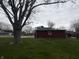Backyard view of the additional garage/shed building, situated on a large lot with mature trees at 216 Golf Club Rd, Anderson, IN 46011