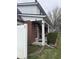 Side view of the red brick home, showing the covered porch, green landscaping, and white privacy fence at 216 Golf Club Rd, Anderson, IN 46011