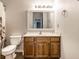 A bathroom with a wood vanity, a white sink, a decorative mirror, and a toilet at 2615 N Delaware St, Indianapolis, IN 46205