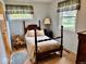 Charming bedroom featuring wood-framed bed, side table with lamp, and two windows at 3601 N Oakwood Ave, Muncie, IN 47304