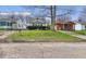 Shows the front yard with a small lawn in need of mowing, surrounded by neighboring houses at 3845 E 32Nd St, Indianapolis, IN 46218