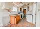 Shows the kitchen's outdated appliances, deteriorated ceiling, flooring, and a partial view of a washing machine and dryer at 3845 E 32Nd St, Indianapolis, IN 46218