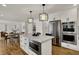 Open kitchen with a large island, stainless steel appliances, modern pendant lighting, and hardwood floors at 4339 Royal Pine Blvd, Indianapolis, IN 46250