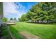 Fenced backyard with mature pine trees, a well-manicured lawn and a small wooden deck at 4786 N Mill Ct, Greenfield, IN 46140