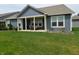 Blue home's backyard featuring a covered patio, lush green lawn, and manicured landscaping at 5269 Parkhurst Xing, McCordsville, IN 46055