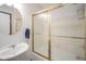 Bright bathroom featuring a pedestal sink and a tub-shower with gold framed sliding glass door at 5555 W Vermont St, Indianapolis, IN 46224