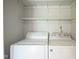 Practical laundry area with washer, dryer, and convenient shelving at 5555 W Vermont St, Indianapolis, IN 46224
