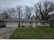 A single story home with a two car garage, gray shingled roof, and patchy front lawn at 5858 E 44Th St, Indianapolis, IN 46226