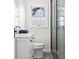 This bathroom features a white vanity, toilet, grey tiled shower and a window with natural light at 5954 Crestview Ave, Indianapolis, IN 46220
