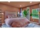 Cozy bedroom with a pink bed, neutral walls, and natural light streaming through large windows at 6185 Evanston Ave, Indianapolis, IN 46220