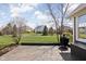 Large grassy backyard with a wooden deck, a grill, and a view of neighboring houses under a sunny sky at 6645 Braemar N Ave, Noblesville, IN 46062