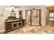 The bathroom boasts travertine flooring, a custom vanity, a glass-enclosed shower, and elegant lighting at 7128 Trail Ridge Ln, Indianapolis, IN 46259