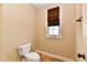 Powder room features a toilet, vinyl floors, a window with a brown blind and tan walls at 7128 Trail Ridge Ln, Indianapolis, IN 46259