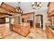 A kitchen with wood cabinets, granite countertops, stainless appliances, and tile floors opens up to an adjacent living space at 7128 Trail Ridge Ln, Indianapolis, IN 46259