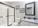 Clean bathroom with a tiled shower, granite counters, and a black framed mirror at 7501 Independence Dr, Zionsville, IN 46077