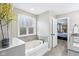 Bright bathroom with a large soaking tub beneath a window, alongside granite counters and access to the bedroom at 7501 Independence Dr, Zionsville, IN 46077