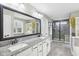 Modern bathroom featuring double sinks, granite counters, a large mirror, and a walk-in shower with glass enclosure at 7501 Independence Dr, Zionsville, IN 46077