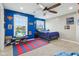 Vibrant bedroom with blue accent walls, a ceiling fan, natural light, and a playful red and blue rug at 7501 Independence Dr, Zionsville, IN 46077