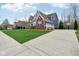 Suburban home featuring a three-car garage, a basketball hoop, complemented by a well-kept lawn and mulched garden at 7501 Independence Dr, Zionsville, IN 46077