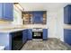 Well-lit kitchen featuring blue cabinets, tile backsplash, and stainless-steel appliances at 908 N Bolton Ave, Indianapolis, IN 46219