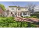 View of the back of the house with a brick patio and yard, enclosed patio, and mixed siding at 908 N Bolton Ave, Indianapolis, IN 46219