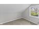 Angled walls highlight a carpeted attic with a window allowing for natural light at 914 N Bancroft St, Indianapolis, IN 46201