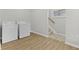 Bright laundry room featuring wood-look flooring, a washer, a dryer, and stairs leading to the upper level at 914 N Bancroft St, Indianapolis, IN 46201
