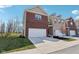 Two-story townhome featuring an attached garage, brick facade, and landscaped front yard under a bright sunny sky at 9725 Thorne Cliff Way # 105, Fishers, IN 46037