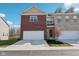 Lovely townhome showcasing an attached garage, brick facade, and well-manicured lawn under a clear blue sky at 9725 Thorne Cliff Way # 105, Fishers, IN 46037