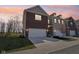 Two-story townhome featuring an attached garage, brick facade, and landscaped front yard under a warm sunset sky at 9725 Thorne Cliff Way # 105, Fishers, IN 46037