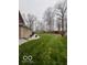 Expansive backyard with mature trees, gravel beds along the house, and a red barn in the distance at 1066 N Dogwood Way, Greenfield, IN 46140