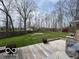 Expansive backyard with wooden deck, lush green lawn, mature trees and red barn-style shed offers space and charm at 1066 N Dogwood Way, Greenfield, IN 46140