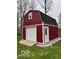 Well-maintained red barn with a garage door and a side door, perfect for storage at 1066 N Dogwood Way, Greenfield, IN 46140