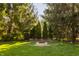 Picturesque backyard featuring a brick fire pit surrounded by lush greenery and mature trees at 10775 Northhampton Dr, Fishers, IN 46038