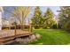 Backyard view featuring a deck, lush lawn, mature trees, and a charming fire pit at 10775 Northhampton Dr, Fishers, IN 46038